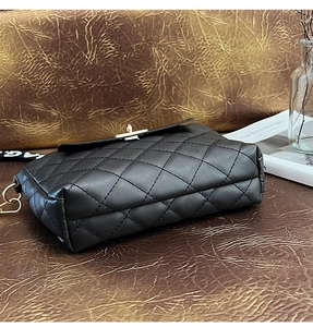 Vue détaillée du sac seau matelassé noir avec fermoir doré sur une surface en cuir