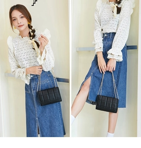 Detail of black quilted chain bag featuring elegant gold hardware and textured finish