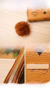 Detail of faux leather wallet with orange-brown monogram pattern and plush ball charm