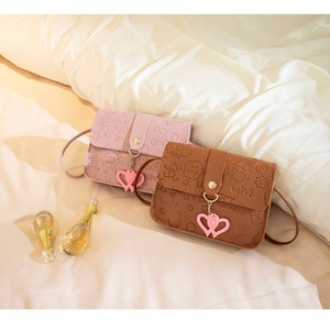 Detail of embossed leather mini crossbody bags with heart charms in pink and brown