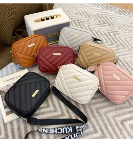 Detailed flat lay of quilted mini camera bags in seven colors with wide lettered straps