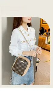 Asian model wearing a patterned crossbody camera bag with adjustable strap and gold trim