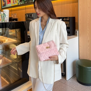 Pink plush crossbody bag with diamond quilting and gold chain strap on female model