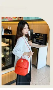 Detail of vibrant orange quilted backpack with gold metal logo and sleek zipper design