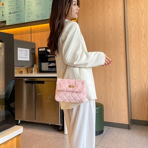 Pink plush quilted crossbody bag with gold chain strap worn over a white blazer