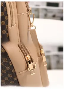 Detail of high-quality golden hardware hooks and dual zipper closures on printed leather bag