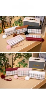 Detailed close-up of a long checkered wallet with a plush pom-pom charm and wrist strap