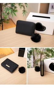 Detail of black quilted mini purse with gold zipper and stylish faux fur pompom keychain