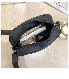 Internal storage of black quilted crossbody bag showing smartphone and makeup items
