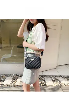 Outdoor shot of a black quilted camera bag featuring a patterned wide fabric strap
