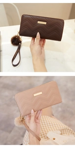 Close-up of quilted long wallets with wrist straps and plush ball charms in brown and beige