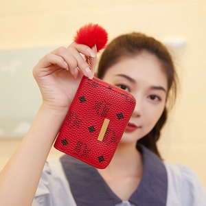 Red printed card wallet with plush pompom keychain and zip closure held by model