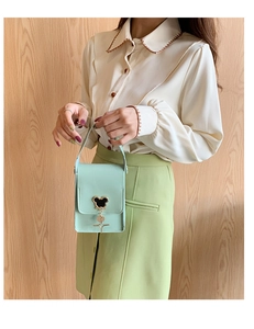 Detail of mint green mini bag with metallic mouse icon and star pendant on flap