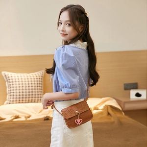 Brown cartoon embossed PU leather square crossbody bag worn by a model in a bedroom