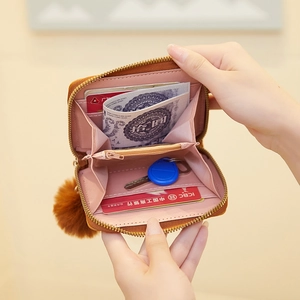 Brown women's zip wallet with pink interior, card slots, and stylish pompom keychain
