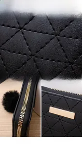 Detail view of black quilted leather texture with smooth zipper and pompom charm