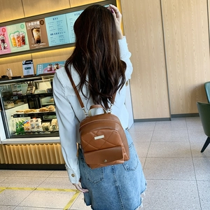 Brown quilted leather backpack for women with metal detail shown on model back