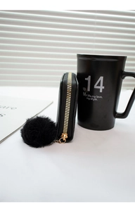 Detail of black faux leather mini wallet with embossed texture and gold zipper charm