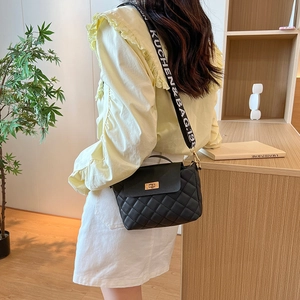 Sac seau matelassé noir avec large bandoulière en tissu porté par un mannequin