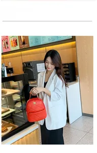 Elegant woman in white suit styling a red quilted mini backpack with gold hardware