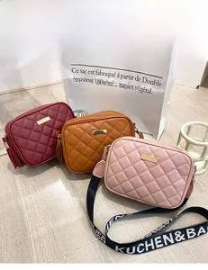 Detail of quilted crossbody bags in burgundy, tan, and pink with tassel and wide strap