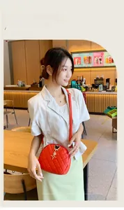 Détail du sac coquillage rouge matelassé avec bandoulière et pendentifs en métal