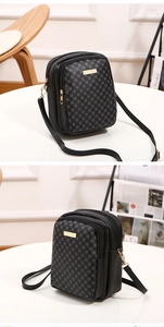 Detail of black crossbody bag with grey geometric pattern and gold-tone zippers