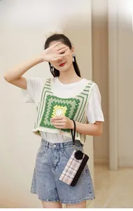 Model wearing a handmade crochet vest with green, yellow, and white geometric patterns