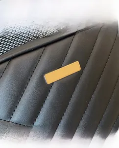 Macro detail of black quilted leather texture and polished gold metal brand plate