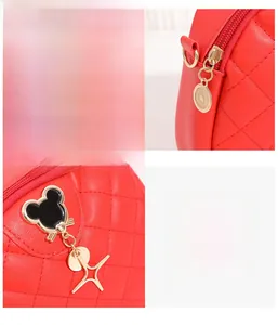 Détail du sac matelassé rouge avec fermeture éclair dorée et breloques étoiles