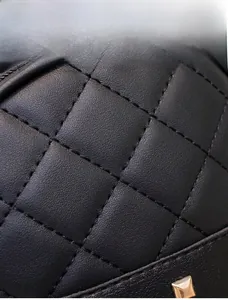 Detail of black quilted leather texture with precise stitching and gold square stud