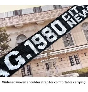 Detail of wide woven shoulder strap featuring black and white embroidered letters