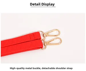 Détail d'une bandoulière en cuir rouge avec fermoirs dorés et coutures précises