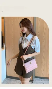 Close-up of pink quilted crossbody bag with metal plaque on a lifestyle model