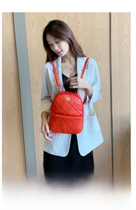 Detail of red quilted faux leather mini backpack with golden logo and metal zipper