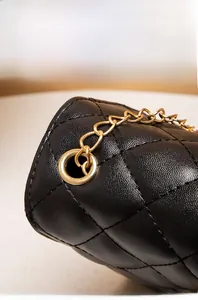 Detailed close-up of quilted black leather texture and gold metal chain hardware