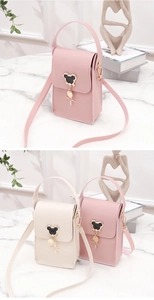 Detail of mini crossbody bags in pink and cream with metal pendants on marble table