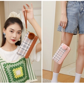 Close-up of checkered long wallet with matching wristlet and soft pompom charm detail