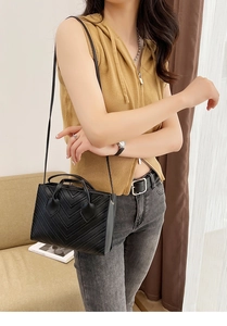 Detail of black quilted mini tote bag featuring V-shaped stitching and dual handles