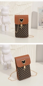 Detail of crossbody phone bag with brown leather flap and mouse-shaped metal hardware