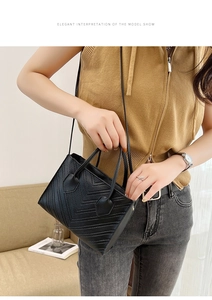 Detail of elegant black quilted crossbody handbag with V-stitch pattern on model
