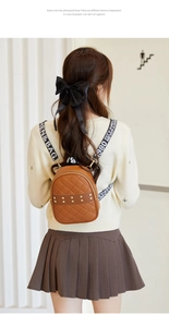 Detail of brown quilted mini backpack with gold studs and lettered wide strap
