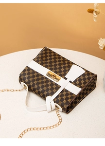 Detail of vintage clover print handbag with white bow accent and gold chain strap