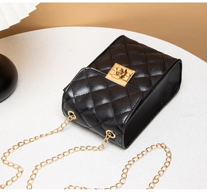 Close-up of quilted black leather camera bag featuring gold metal chain and twist lock