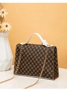 Detail view of printed crossbody bag featuring golden chain strap and white contrast stitching