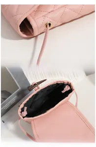 Detailed view of pink quilted leather bag featuring a brown buckle and inner drawstring lining