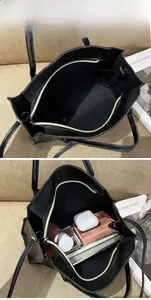 Detail of the black leather tote bag interior featuring a smooth metal zipper pocket