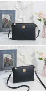 Detail of black quilted mini bag with golden metal plate and chain hook on a white background