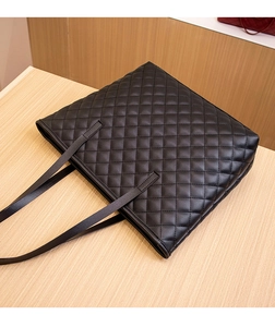 Detailed view of black quilted faux leather tote bag with diamond stitching and slim straps