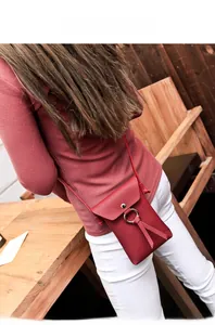 Detail of red pebbled leather mini crossbody bag with metal ring and tassel detail